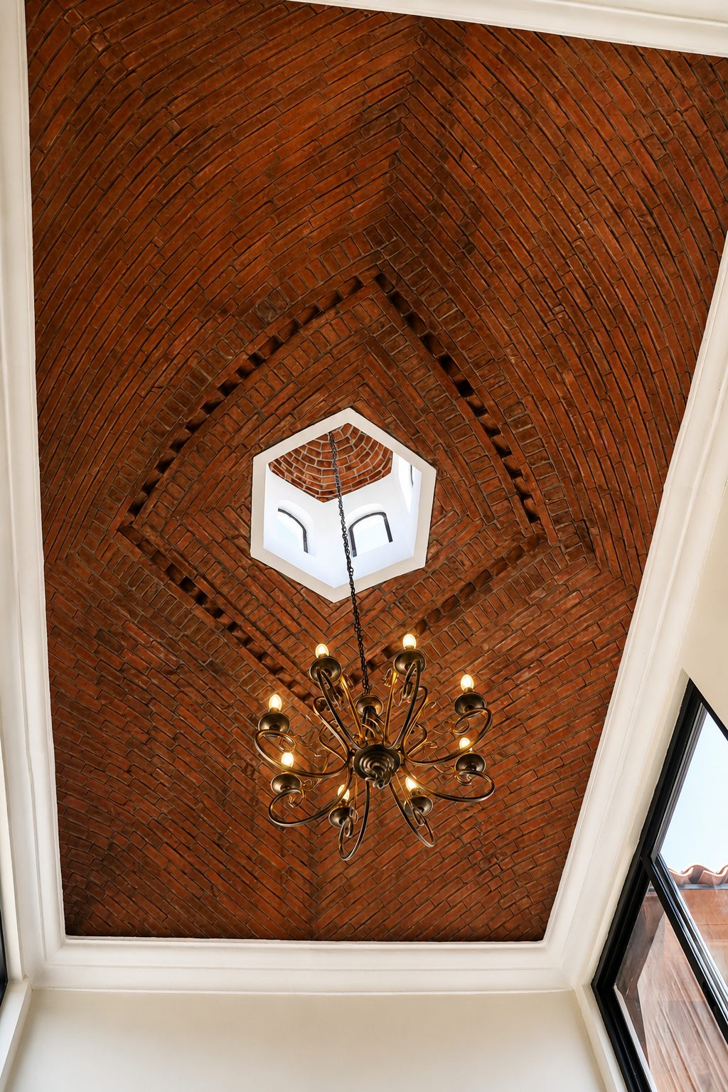Herringbone brick vault ceiling with cupola and chandelier, seen from below