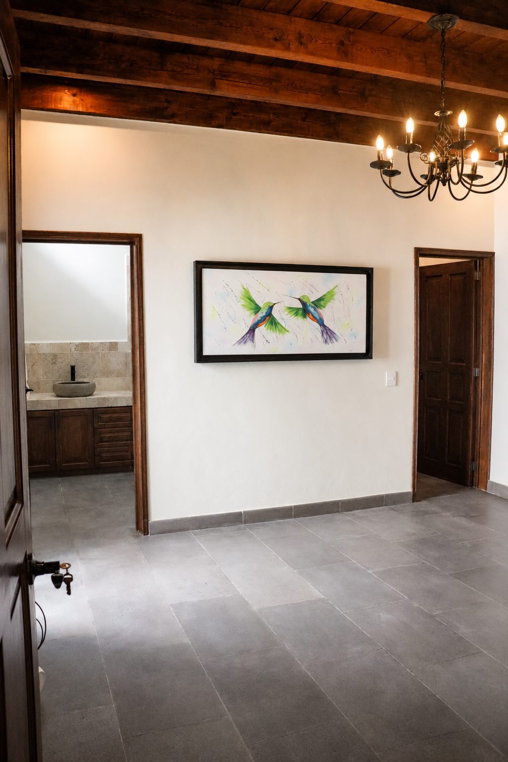 Second floor room with wood-beamed ceiling, chandelier and hummingbird painting