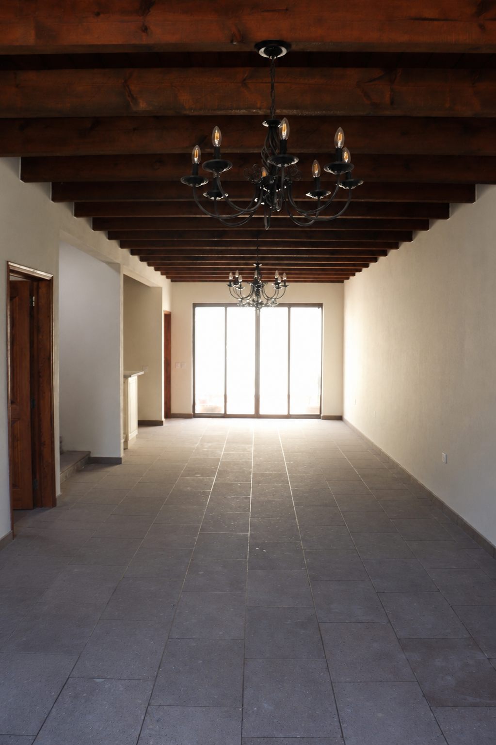 Open living room with wood-beamed ceiling and chandeliers